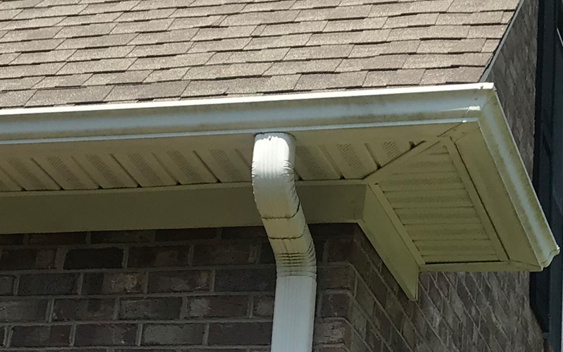 Photo of gutters and downspout at the corner of a brick house